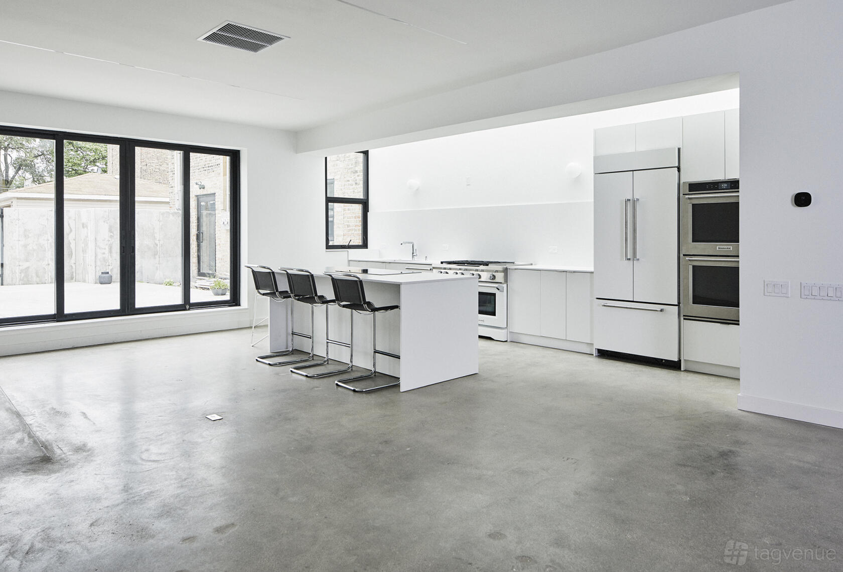 An event venue with floor-to-ceiling windows, a modern kitchen, and polished concrete floors at North Logan Studio.