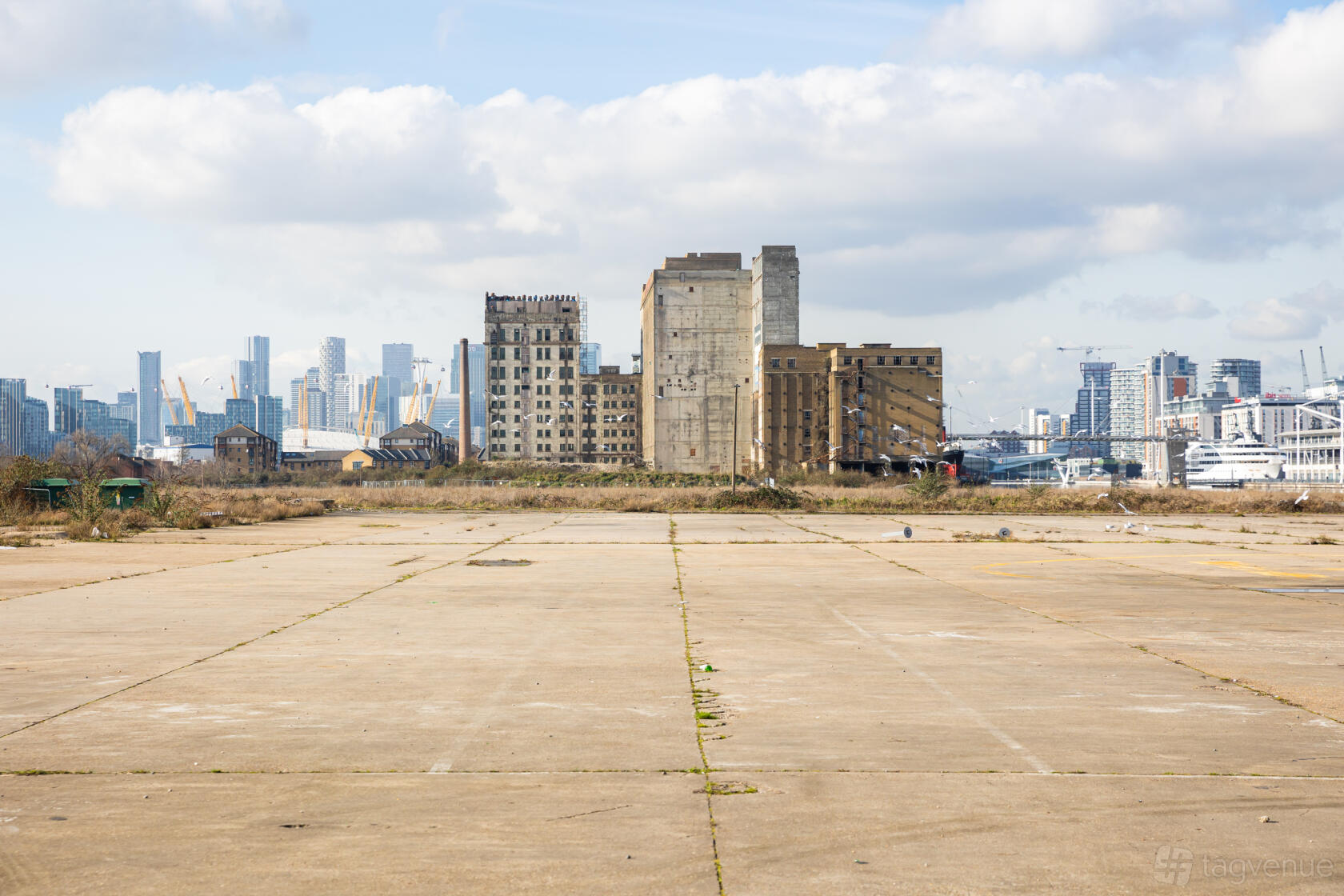 An open concrete event space with city skyline views and industrial buildings at Silverworks Island.