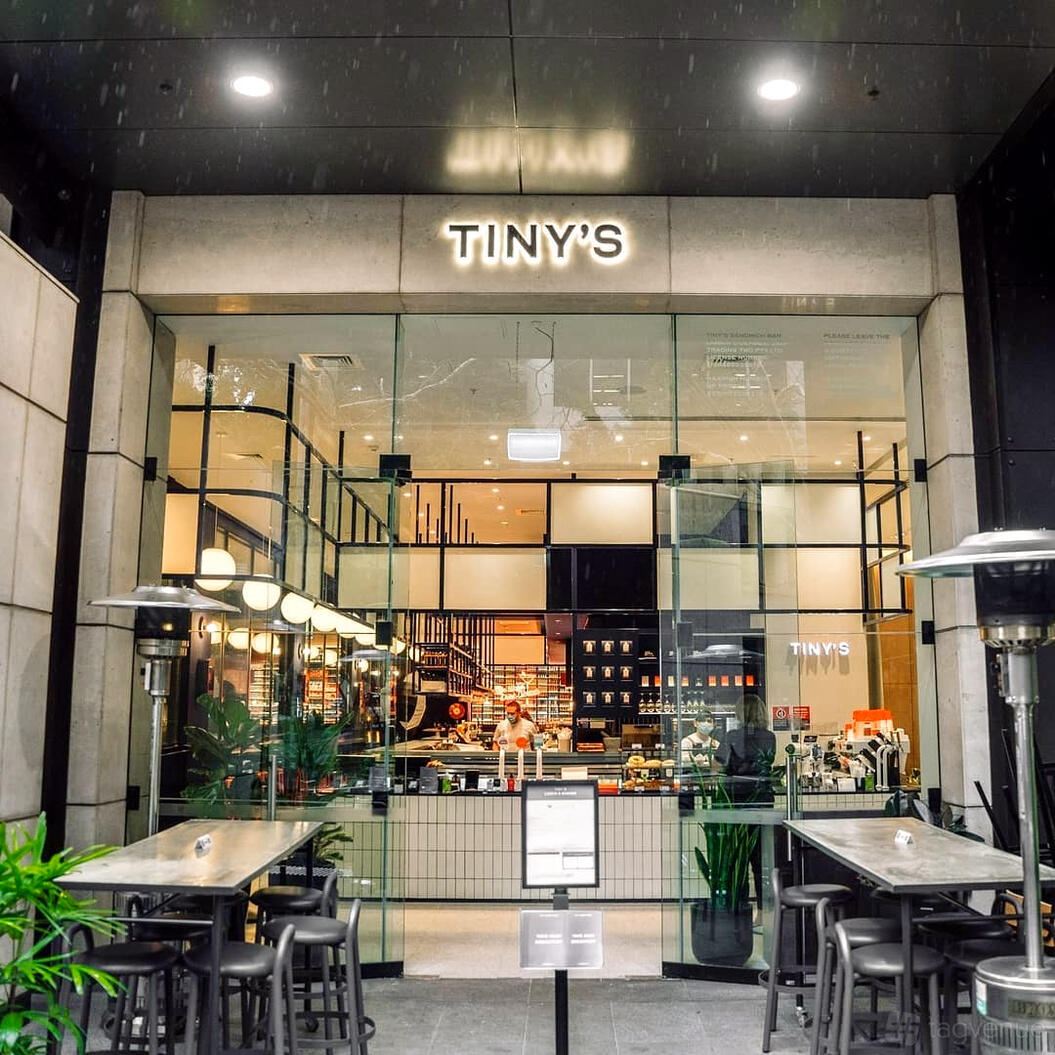 A pub with a glass facade, open counter, and warm lighting at Tiny's Sandwich Bar.