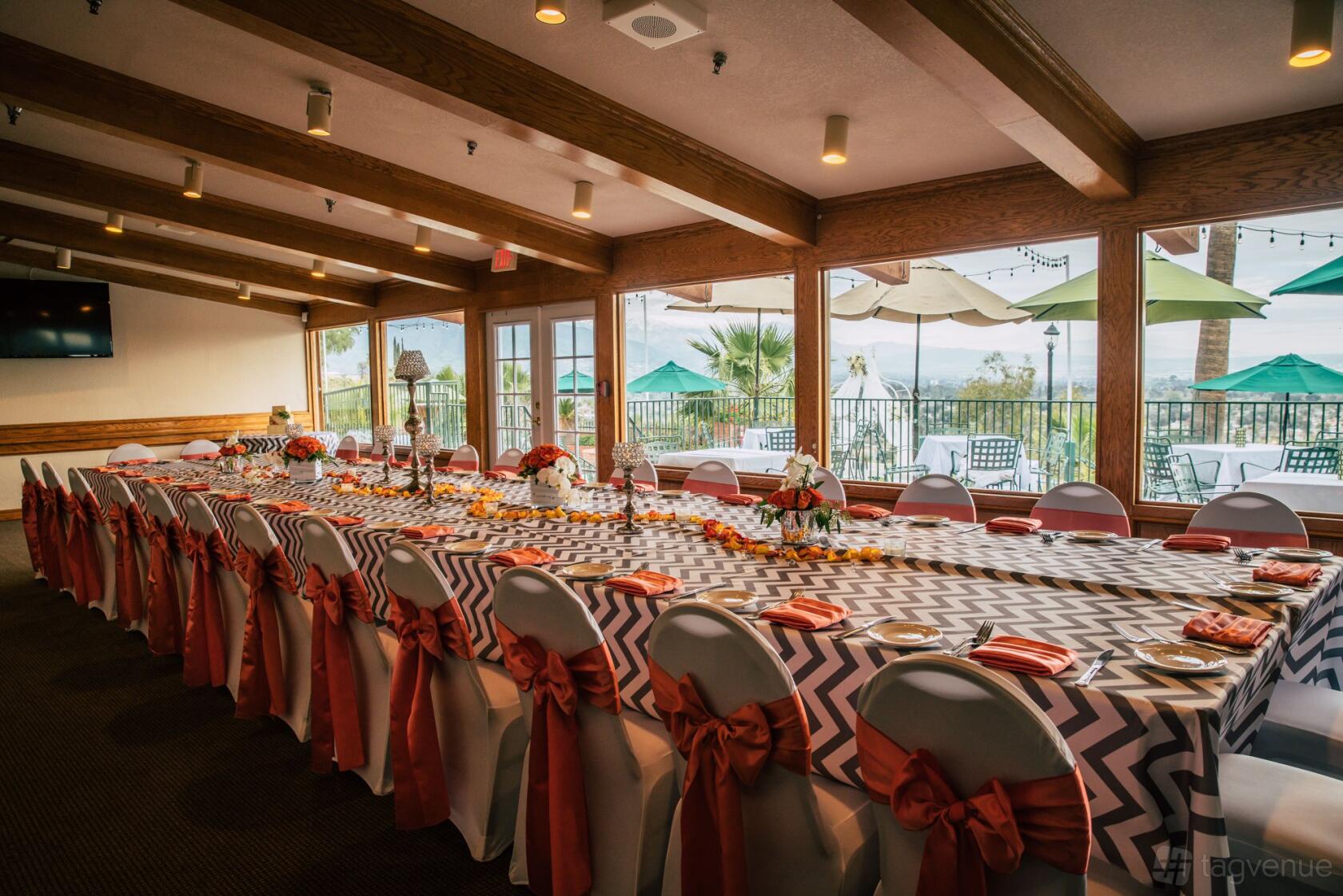 An indoor event space with chevron tablecloths, banquet tables, and large windows overlooking a patio at Hilltop Collection San Bernardino.