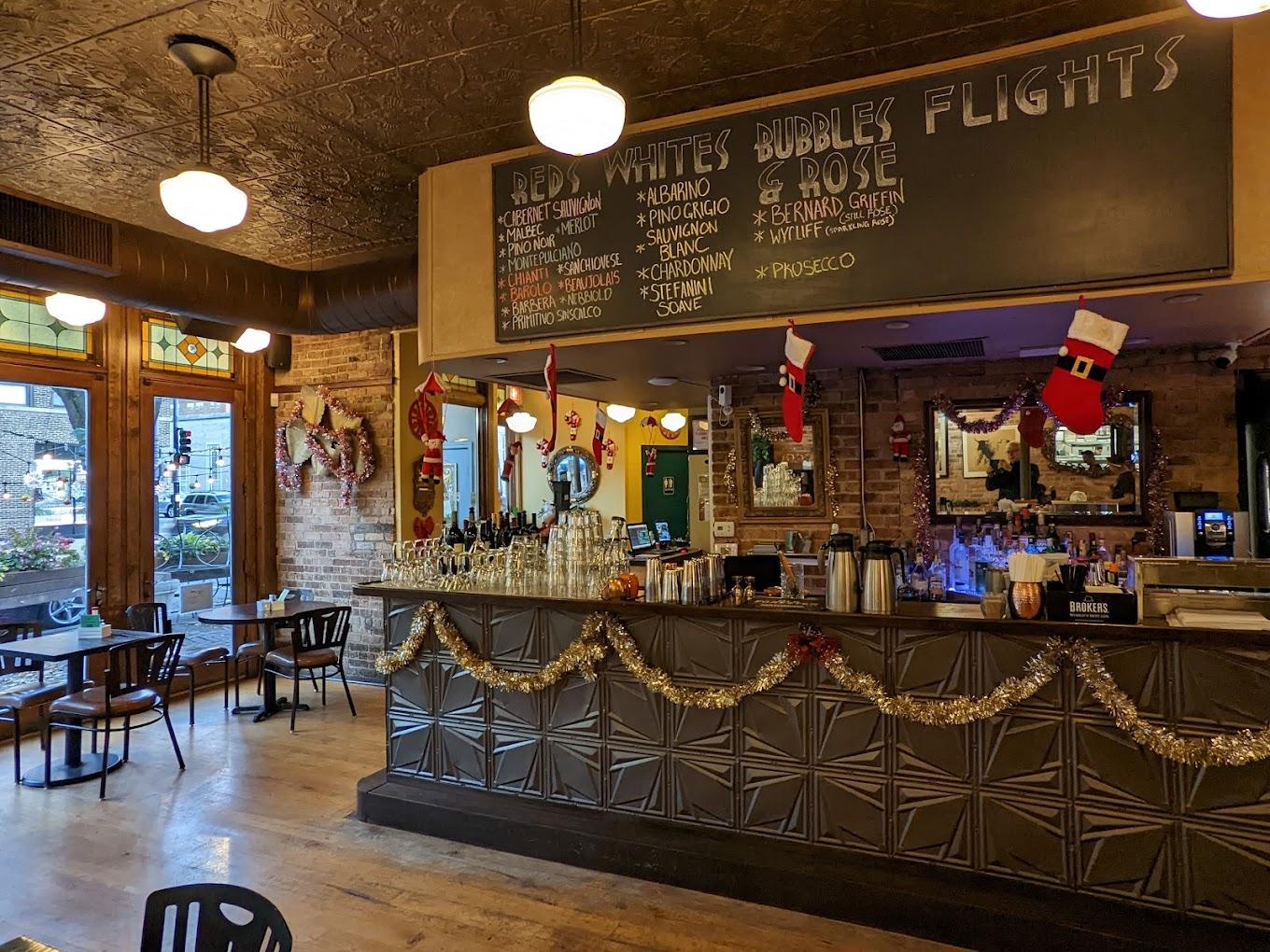 A function room with a decorated bar, holiday garlands, chalkboard wine menu, and exposed brick at Port and Park Bistro.