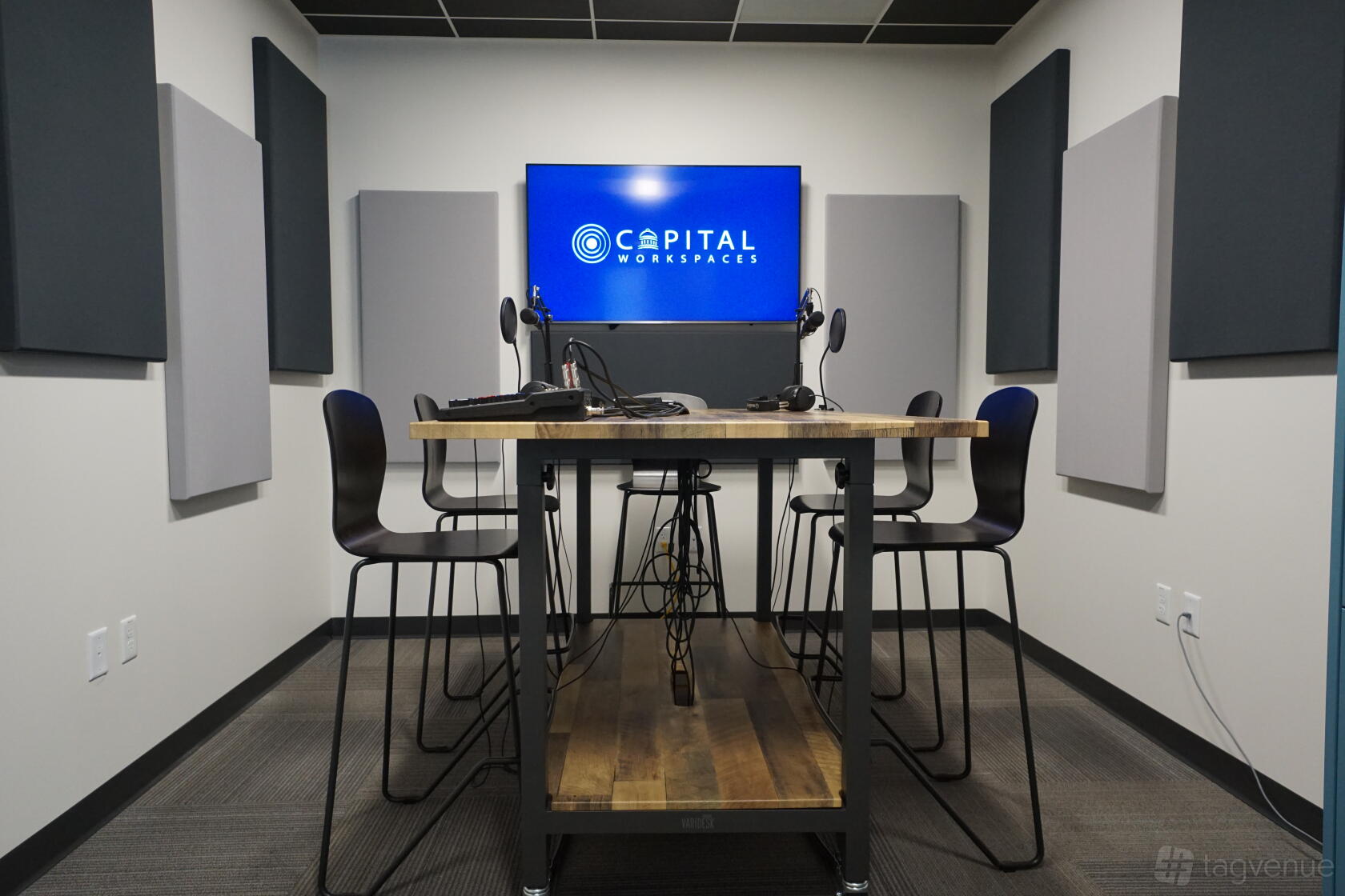 A coworking space with a podcast studio featuring soundproof panels, high stools, and microphones at Capital Workspaces Bethesda.
