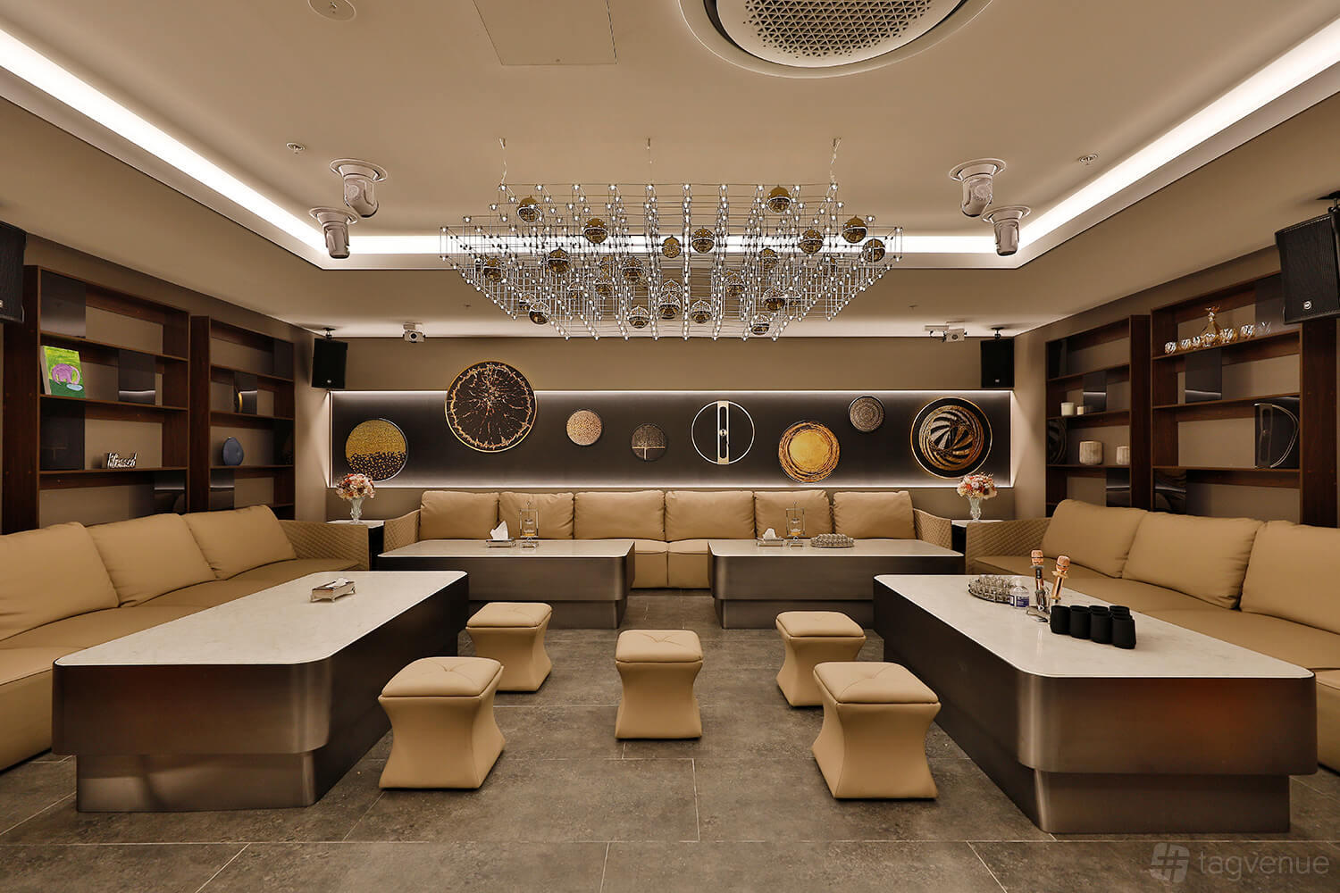 A bar lounge with beige sectional sofas, modern chandeliers, and geometric wall art at Game Republic Karaoke Entertainment Centre.