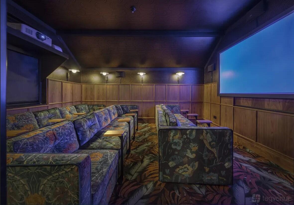 A cinema lounge with patterned armchairs, wood-paneled walls, and a large screen at Everyman Hampstead.