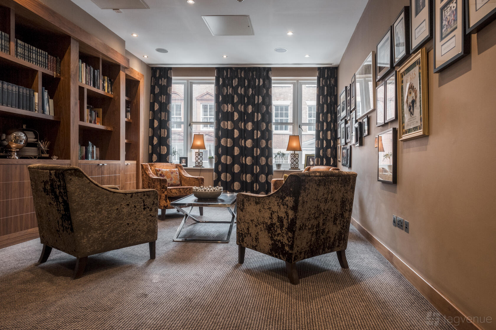 An event venue library with velvet armchairs, built-in bookshelves, and framed artwork at The Chambers.
