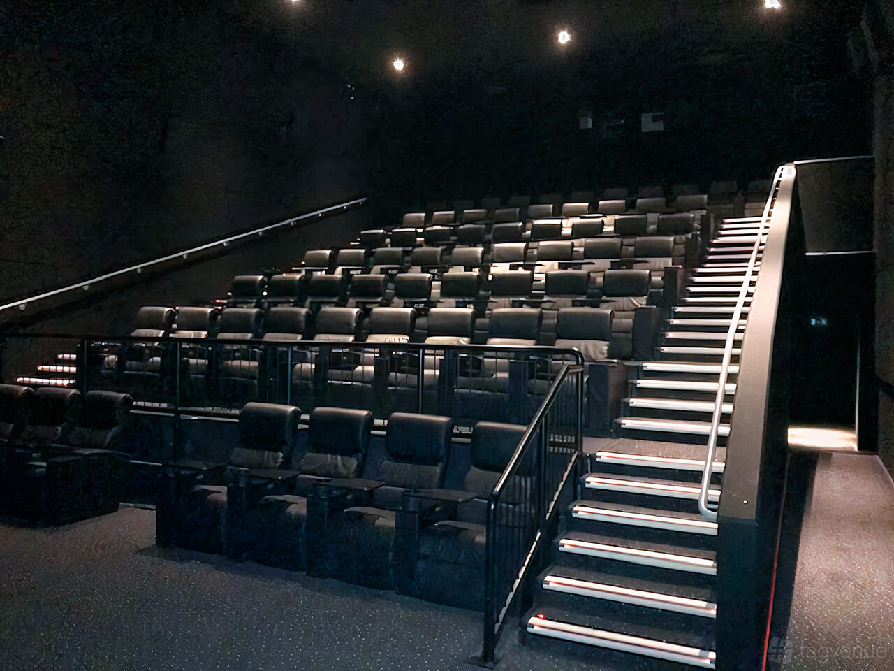 A screening room with tiered rows of black leather recliner seats and illuminated aisle steps at Vue Manchester Quayside.