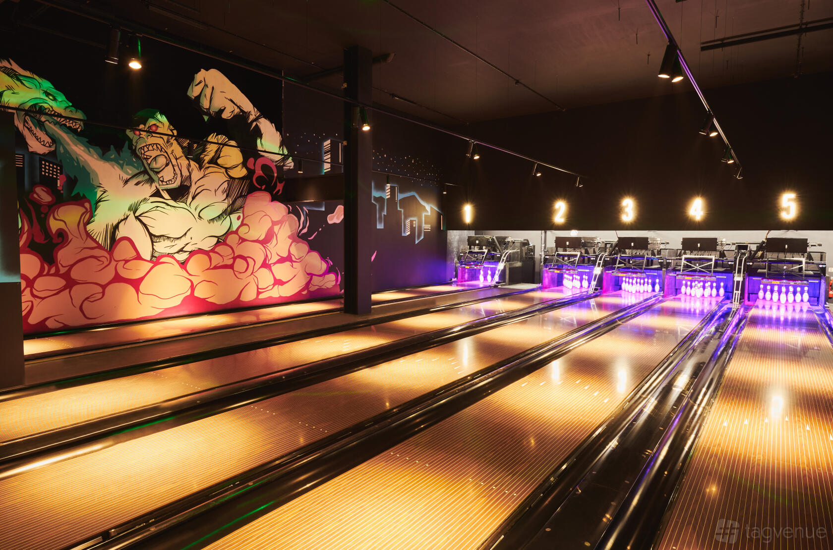 A bowling alley with illuminated lanes, overhead lane numbers, and a colorful mural at The Light Banbury.