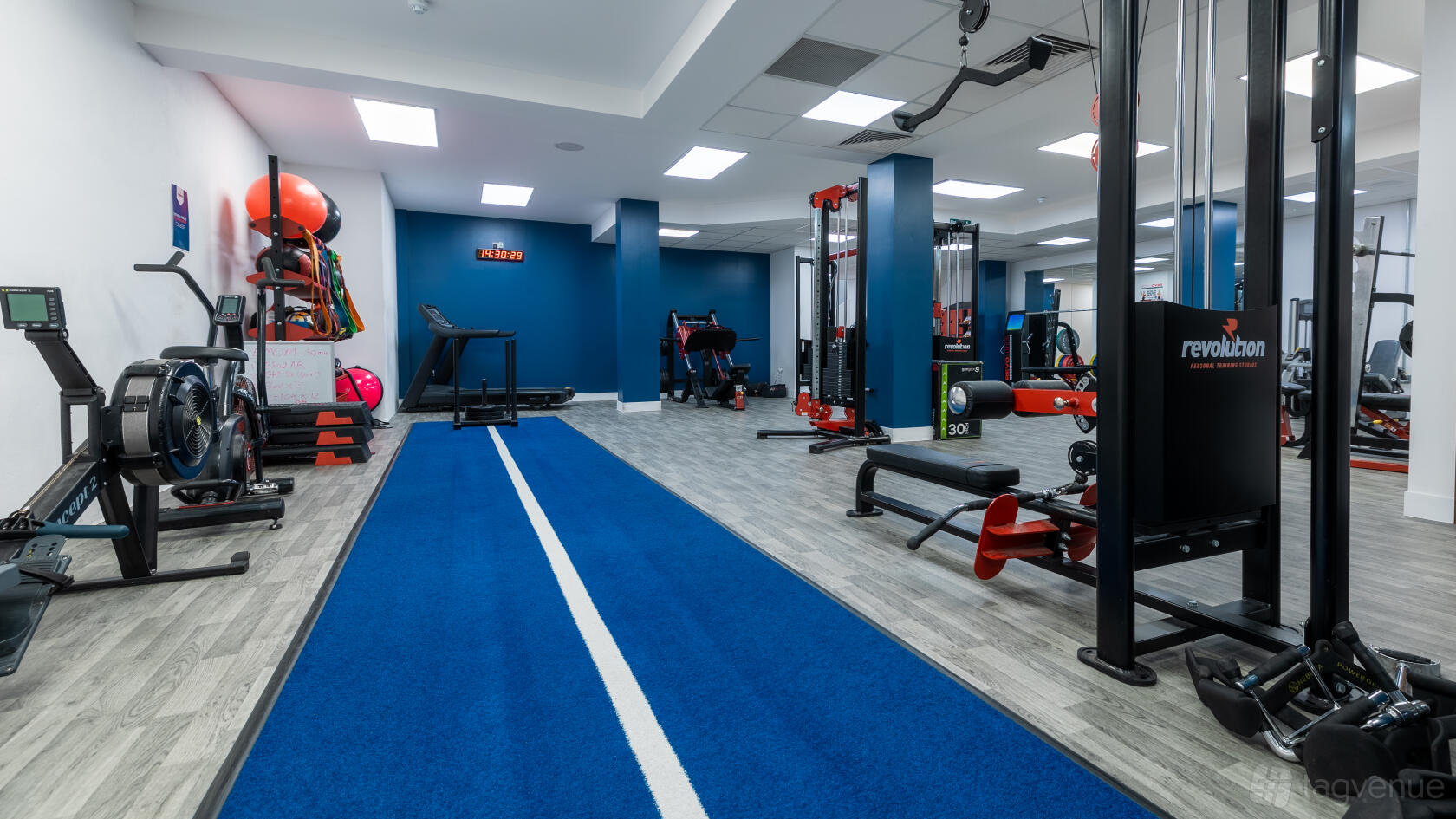 A fitness studio with cardio machines, weights, resistance equipment, and a blue sprint track at Revolution Personal Training Studio Holborn.
