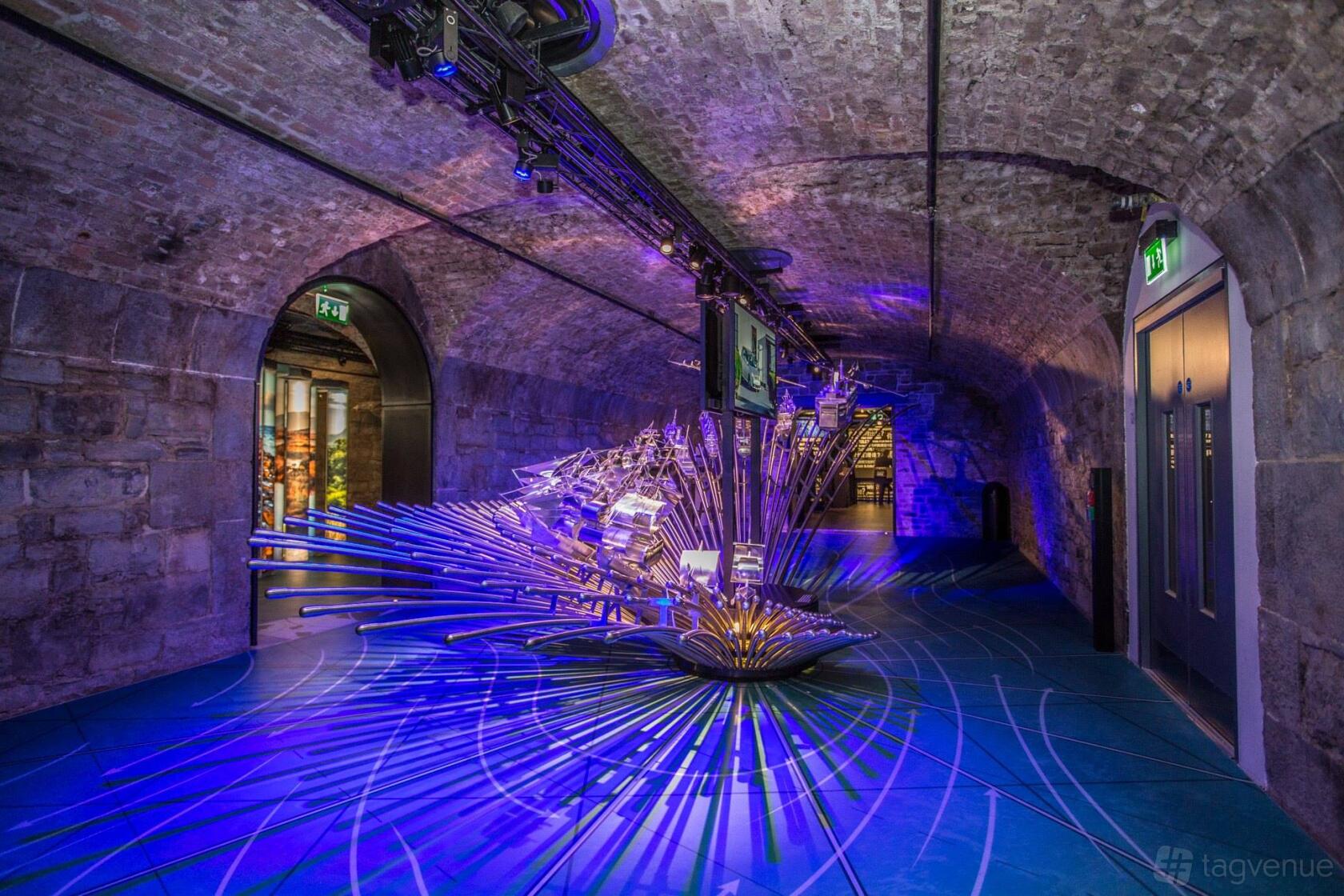 An event venue with arched exposed brick ceilings, dramatic blue lighting, and a central art installation at EPIC & CHQ.