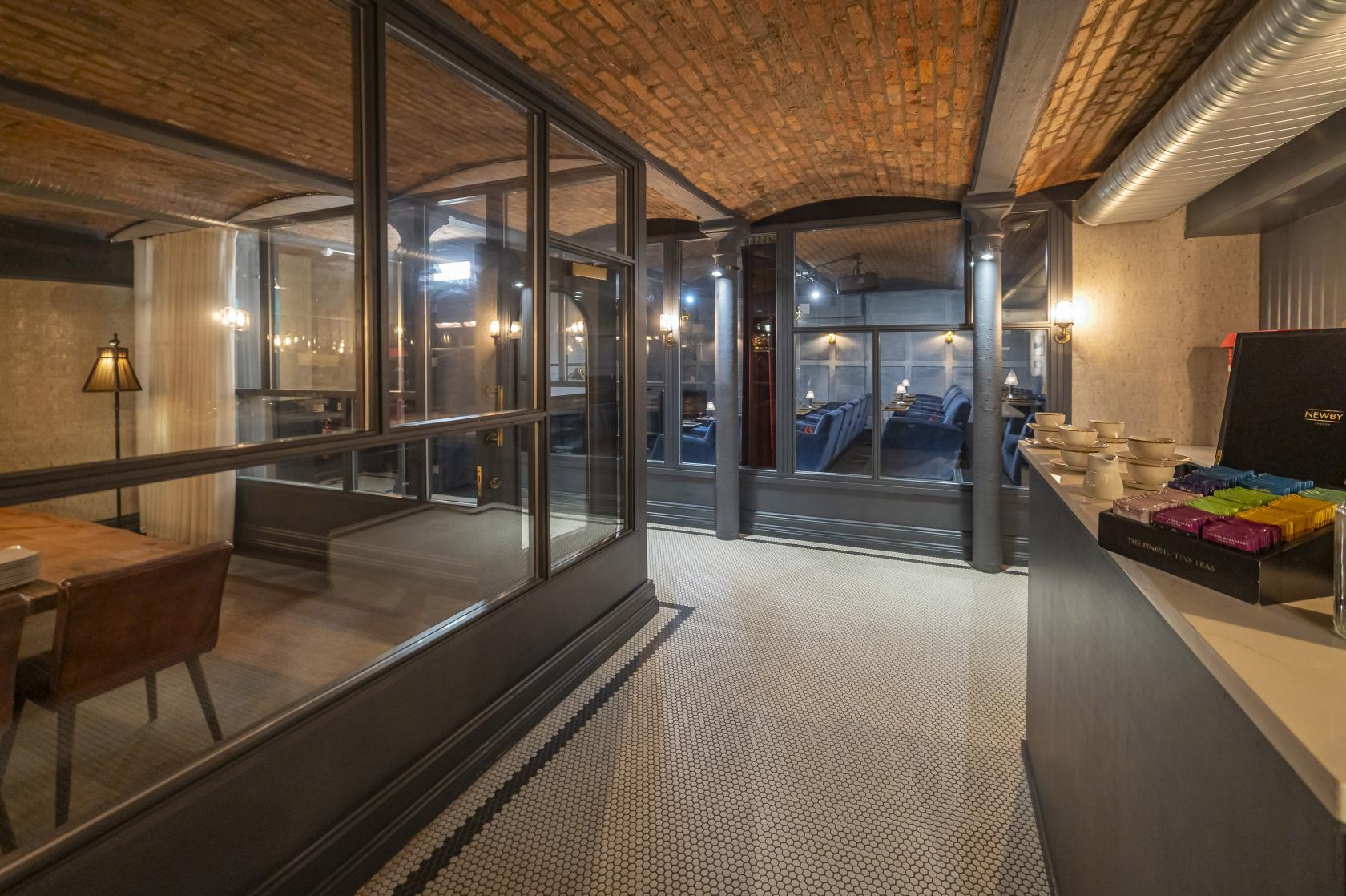 An event space in a hotel with exposed brick ceilings, glass partitions, and mosaic tile flooring at King Street Townhouse.