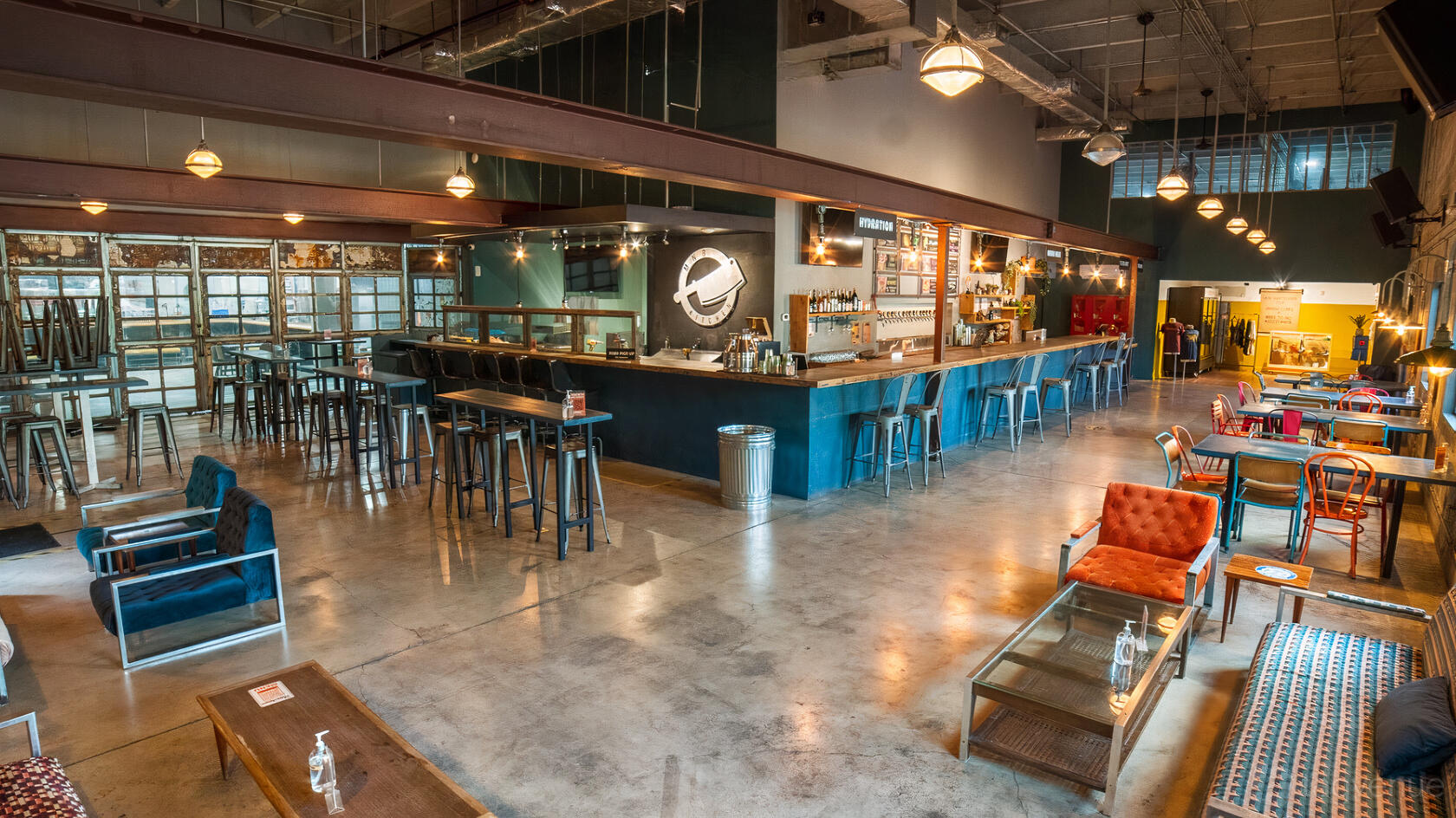 A brewery taproom with a long bar, high-top tables, lounge seating, and industrial lighting at Tripping Animals Brewing Co.