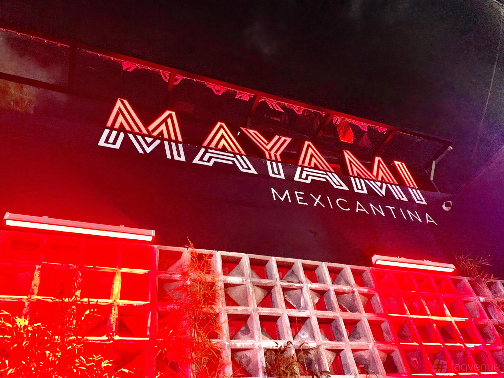 A restaurant exterior with bold neon red signage and patterned concrete wall at Mayami Wynwood.