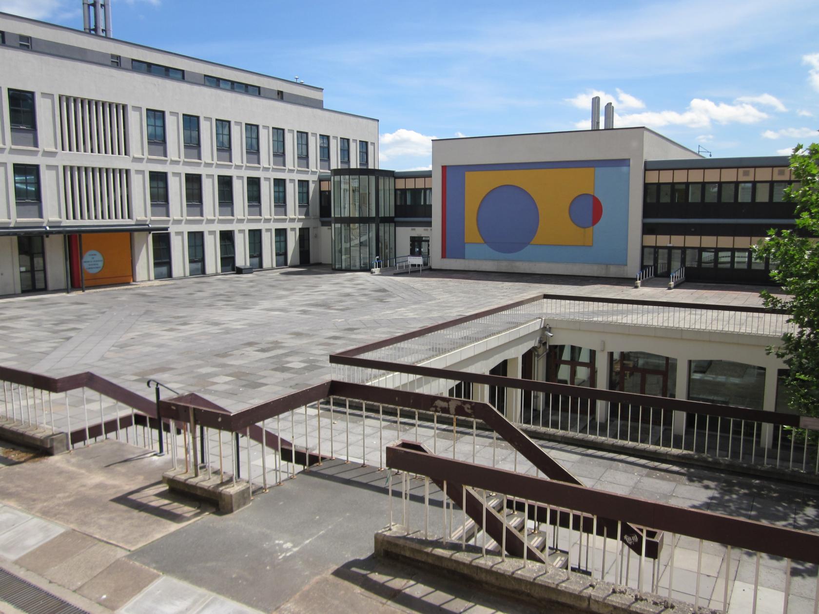 An academic venue with an open paved courtyard and abstract mural on exterior walls at Chemistry Building