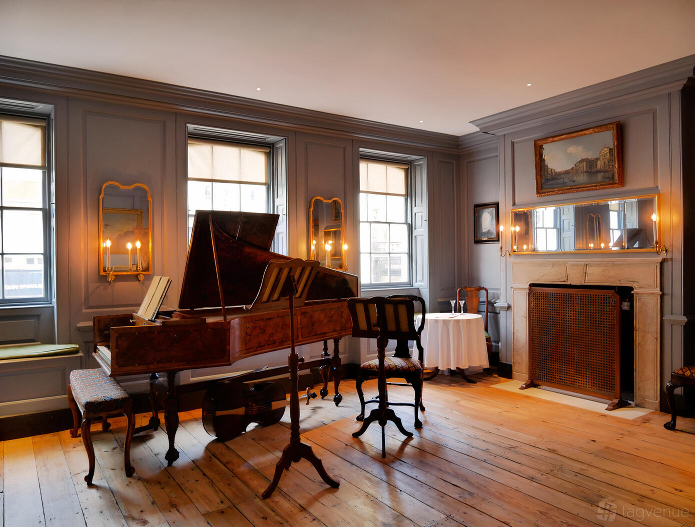 A piano room with wooden flooring, an antique harpsichord, and candlelit wall sconces at Handel Hendrix House.
