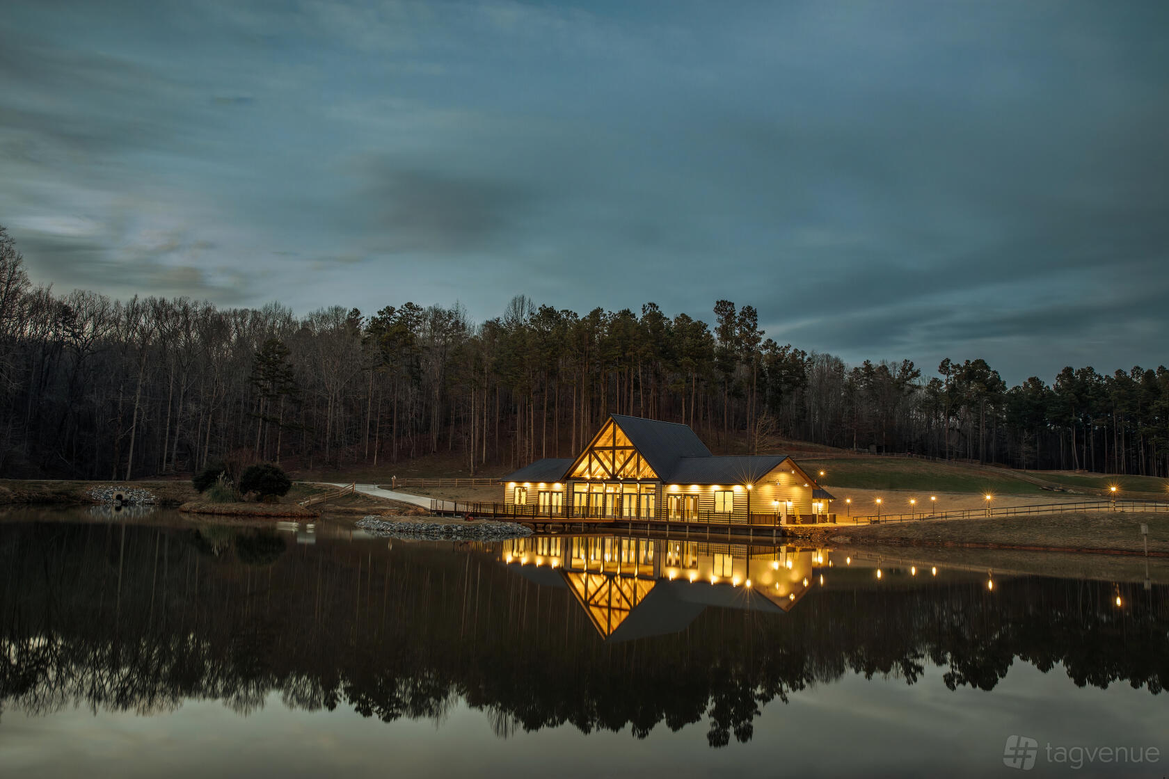 A versatile event space with timber beams and large windows, reflecting on a lakeside at Swan Lake Overlook.