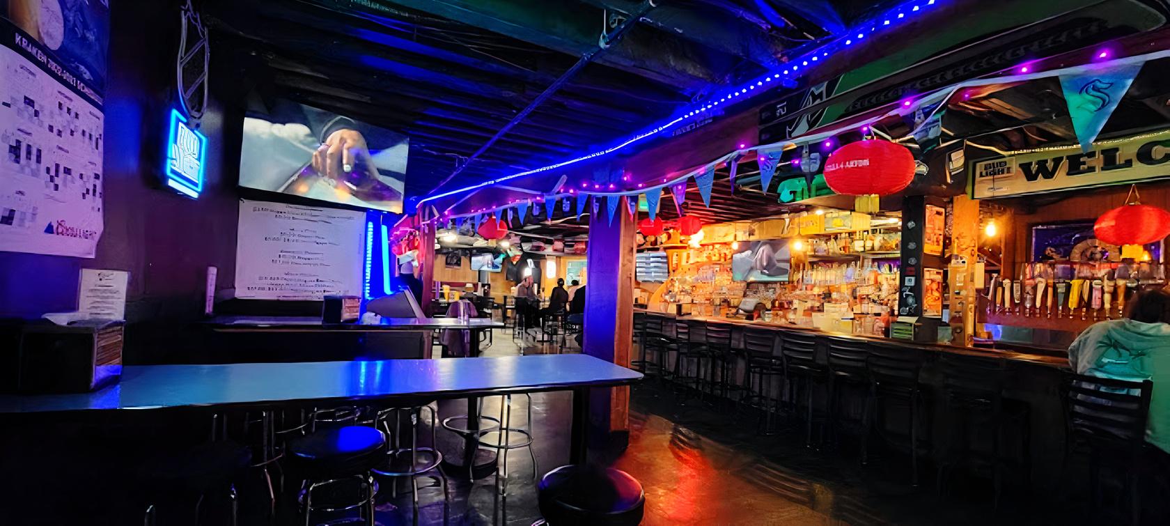 An event space in a bar with string lights, colorful bunting, high tables, and a long counter at Ozzie's in Seattle.