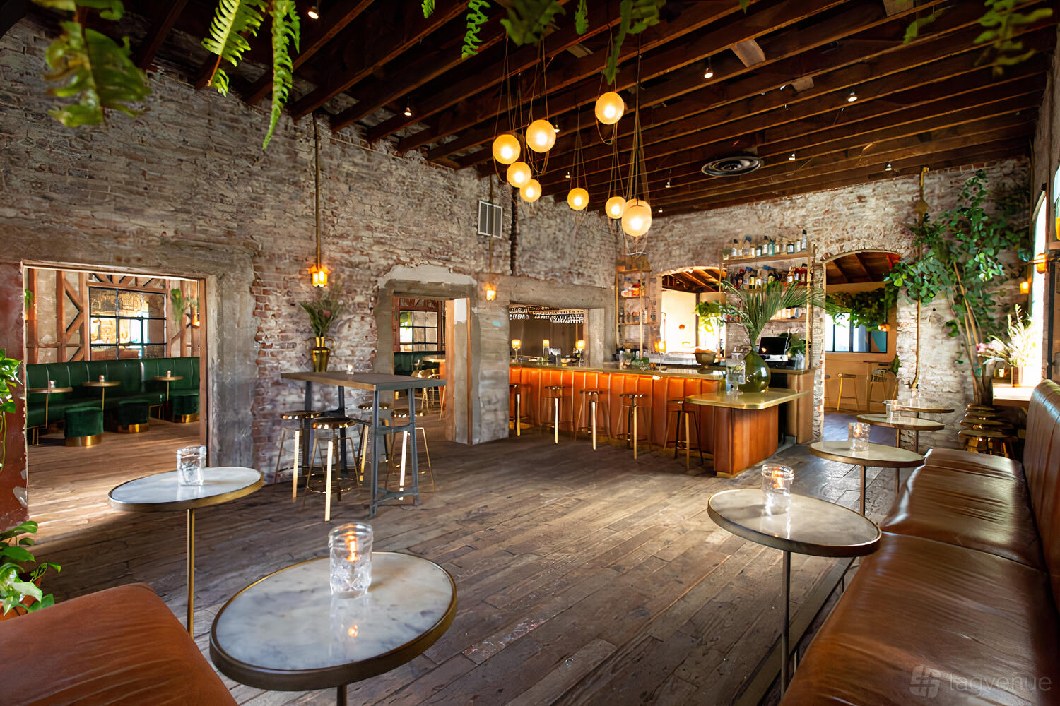 A bar with exposed brick walls, wooden floors, globe pendant lighting, and a marble-top bar at Roosterfish.