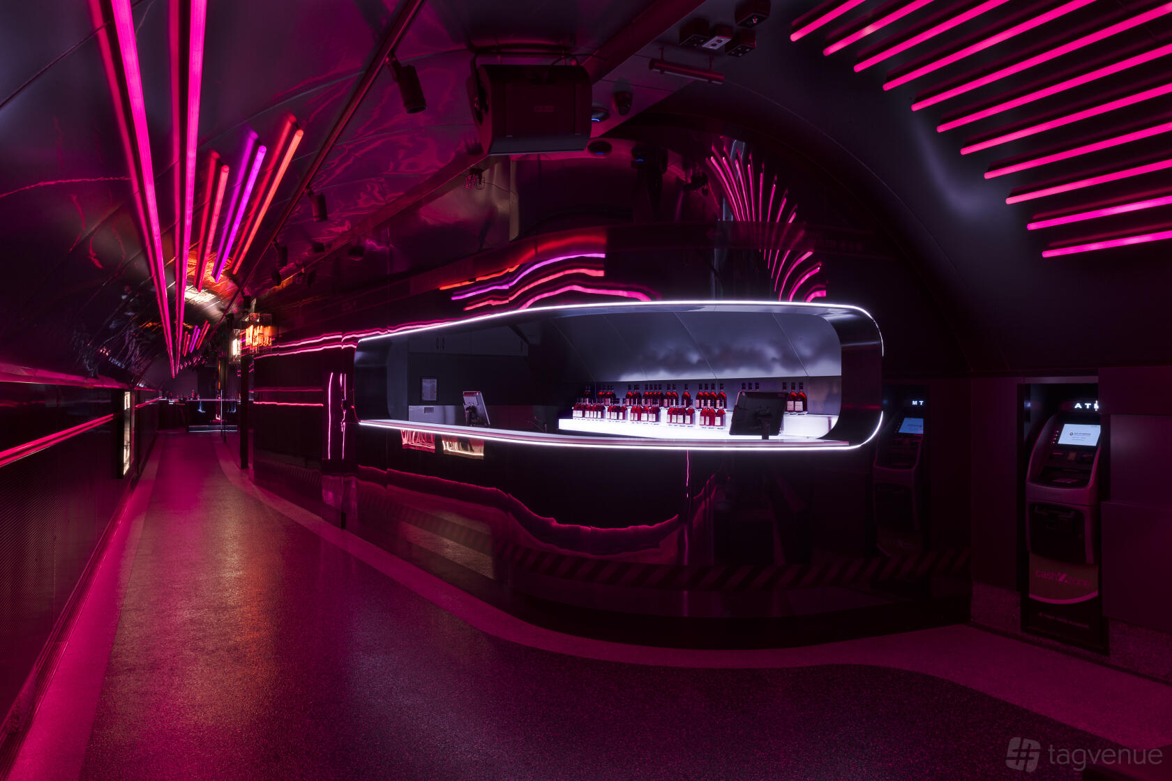 A nightclub event space with neon pink lighting, curved metallic walls, and a sleek illuminated bar at Platform One Nightclub.