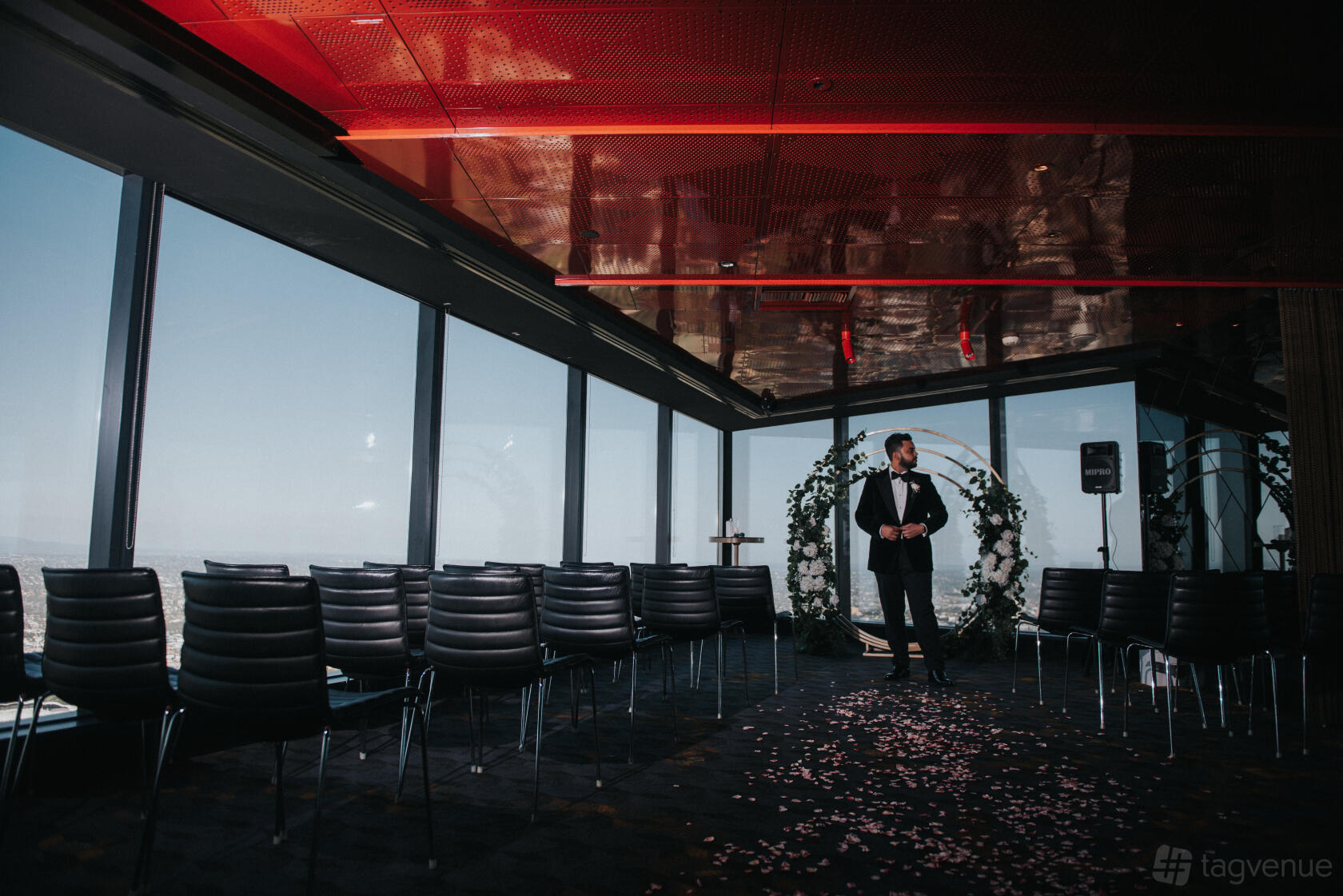 A restaurant with floor-to-ceiling windows, city skyline views, and rows of black chairs at Eureka 89.