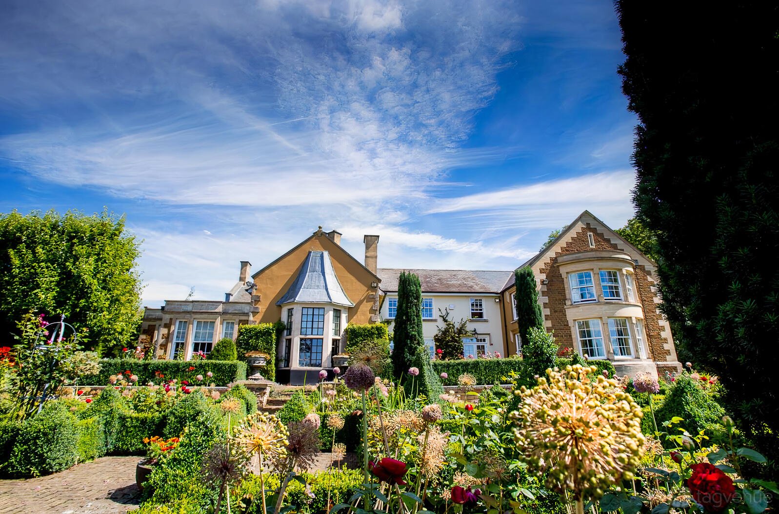 A country house with manicured gardens, stone pathways, and decorative shrubbery at Ladywood Estate.