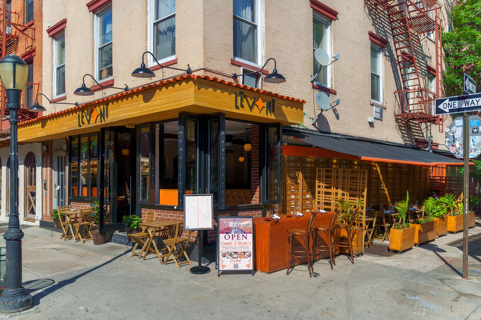 A corner restaurant with sidewalk seating, wooden tables, and large windows at Levant on Smith.