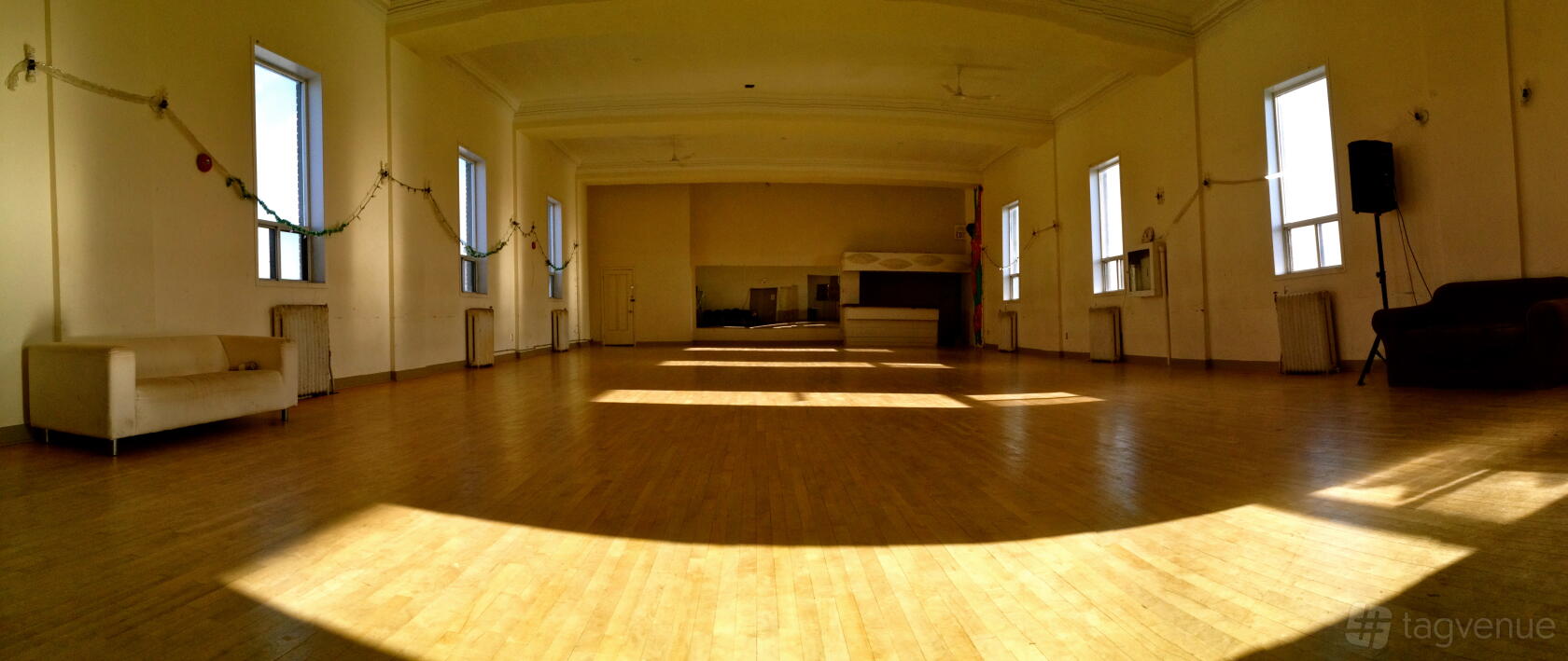 A dance studio with hardwood floors, tall windows, and wall mirrors at Dovercourt House.