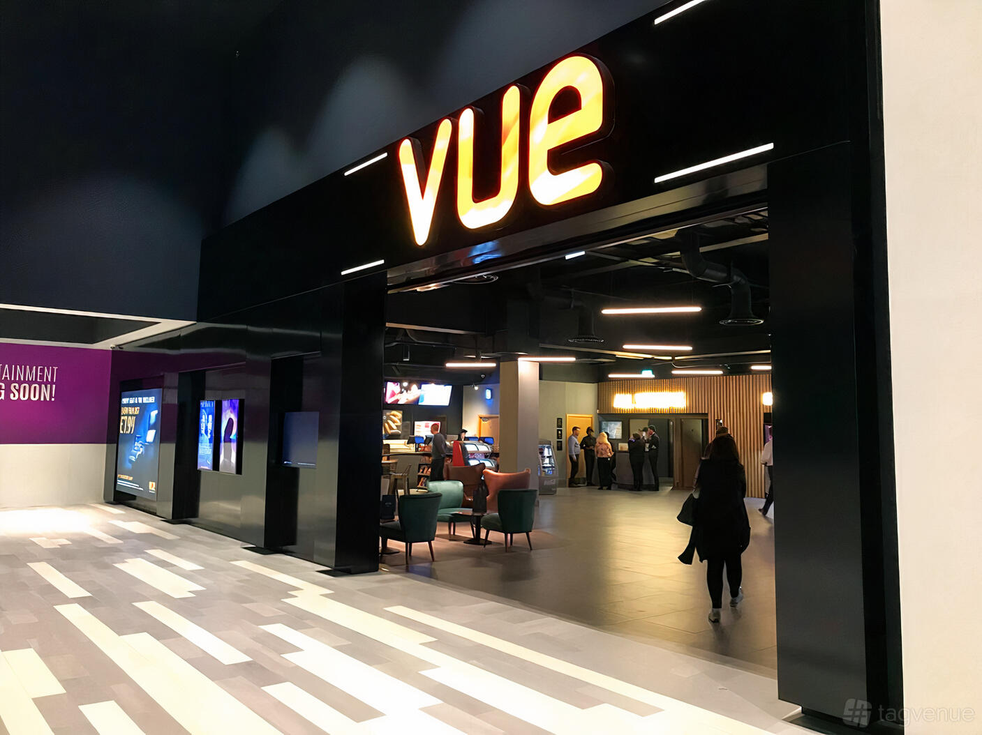 A cinema entrance with illuminated signage, seating area, and digital screens at Vue Manchester Quayside (MediaCityUK).