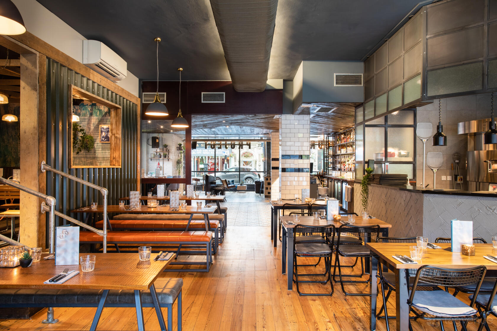 A bar with wooden floors, exposed ceilings, mixed seating, and an open layout at Foundry Project.