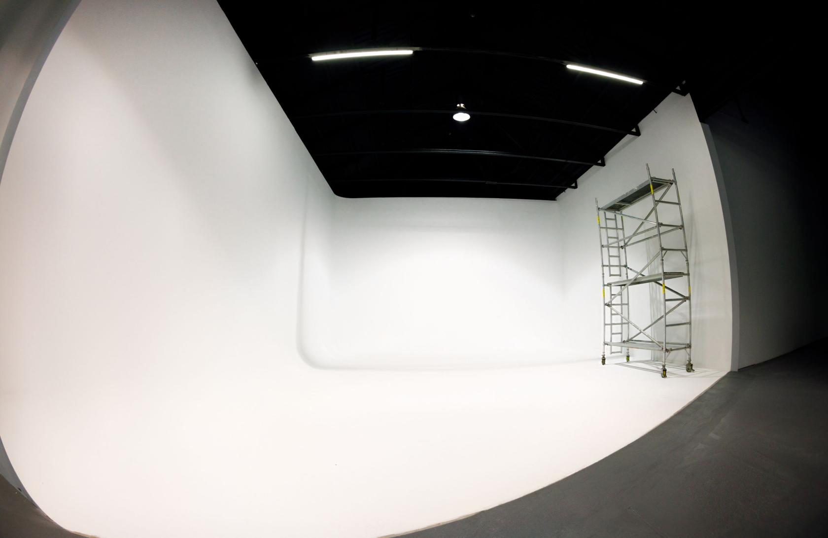 A photo studio with a white cyclorama wall and ceiling lights at Unit F Studios.