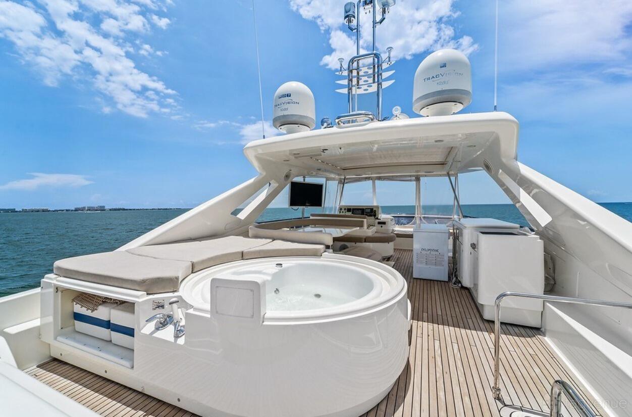 A yacht deck with a round jacuzzi, sun loungers, and open sea views aboard Luxe Charters Ferretti 87.