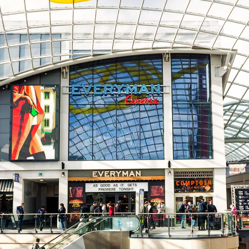 A cinema with a glass facade, large neon signage, and digital display screens at Everyman Leeds.