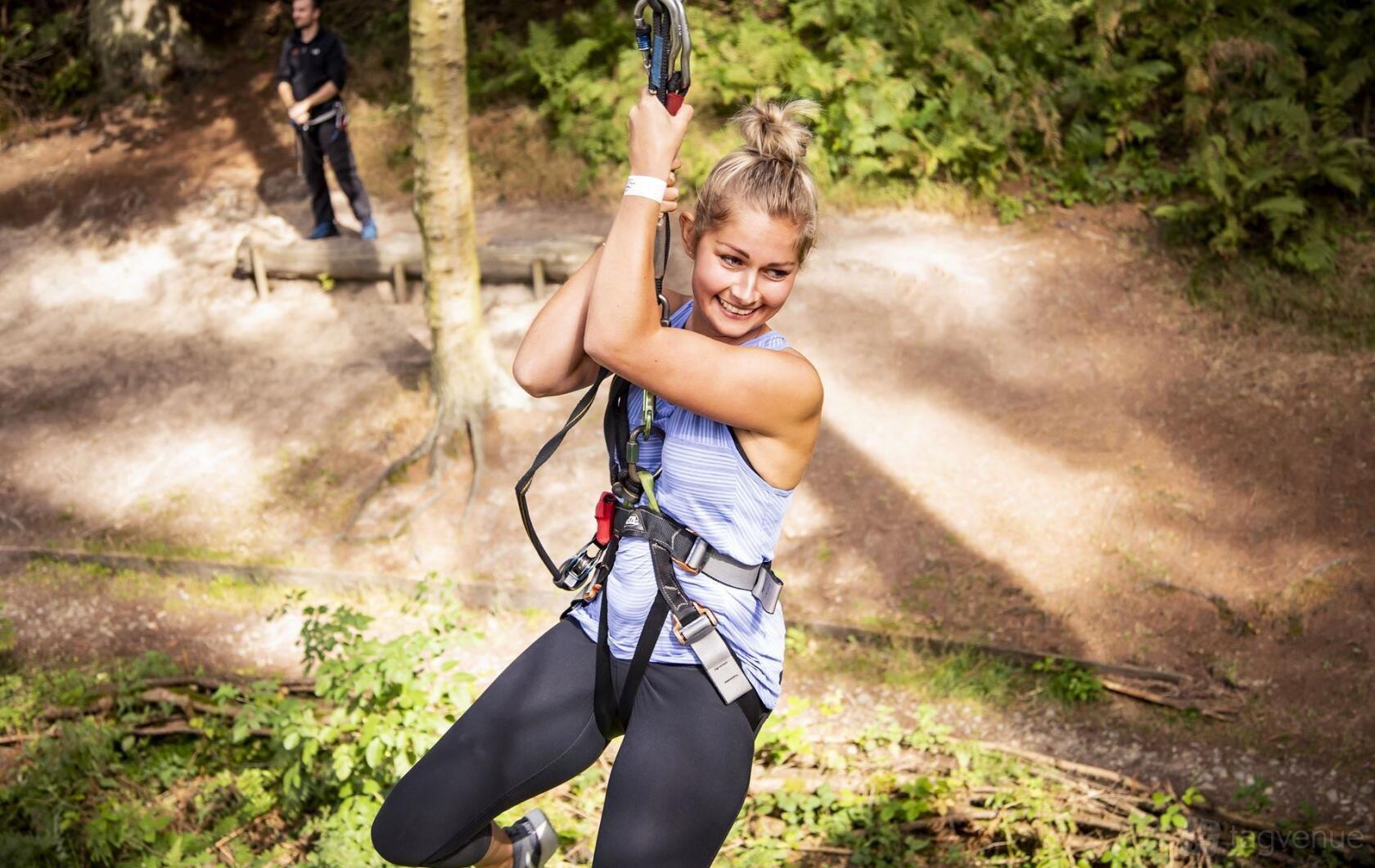 An outdoor adventure course with a participant ziplining through trees at Go Ape Moors Valley.