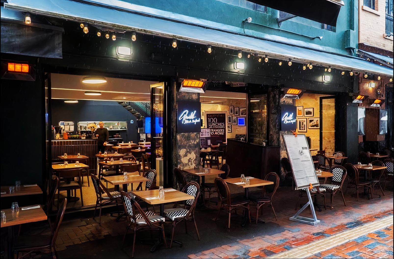 An outdoor dining area with wicker chairs, square wooden tables, and string lighting at Grill Steak Seafood.