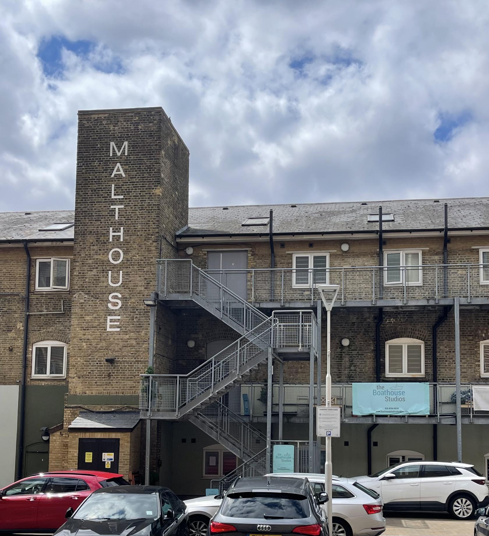An event venue with exposed brick exterior, metal staircase, and large Malthouse signage at Boathouse Studios, Barking.