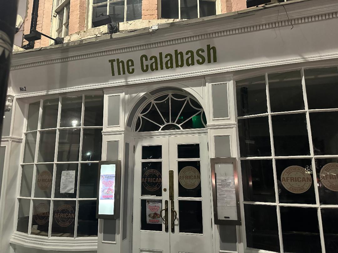 A restaurant with a white-painted facade, large grid windows, and arched transom at Calabash Restaurant & Bar.