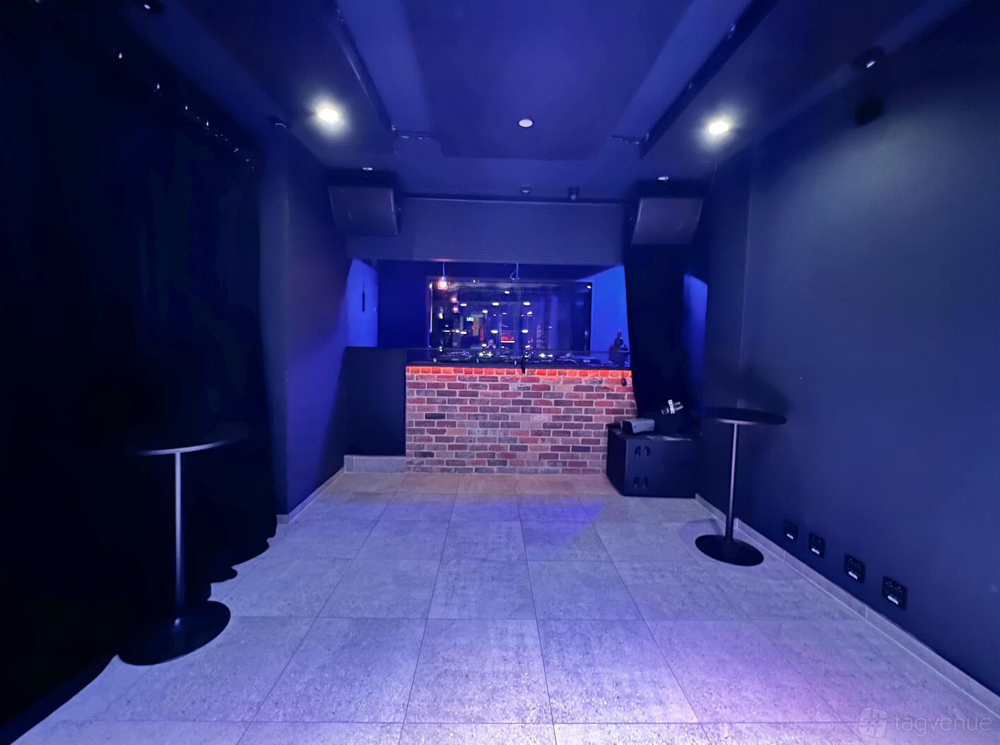 A nightclub with exposed brick DJ booth, dark walls, and blue accent lighting at QQQ ST. Park.