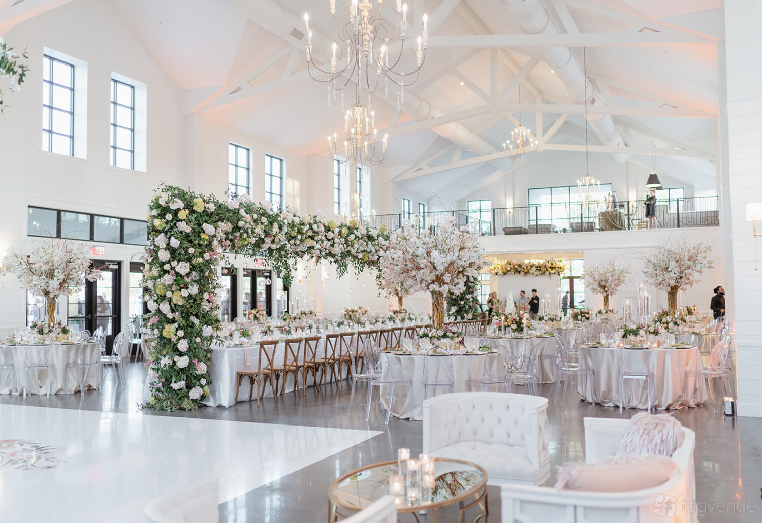 An event venue with vaulted ceilings, large windows, chandeliers, and floral arrangements at Boxwood Manor.