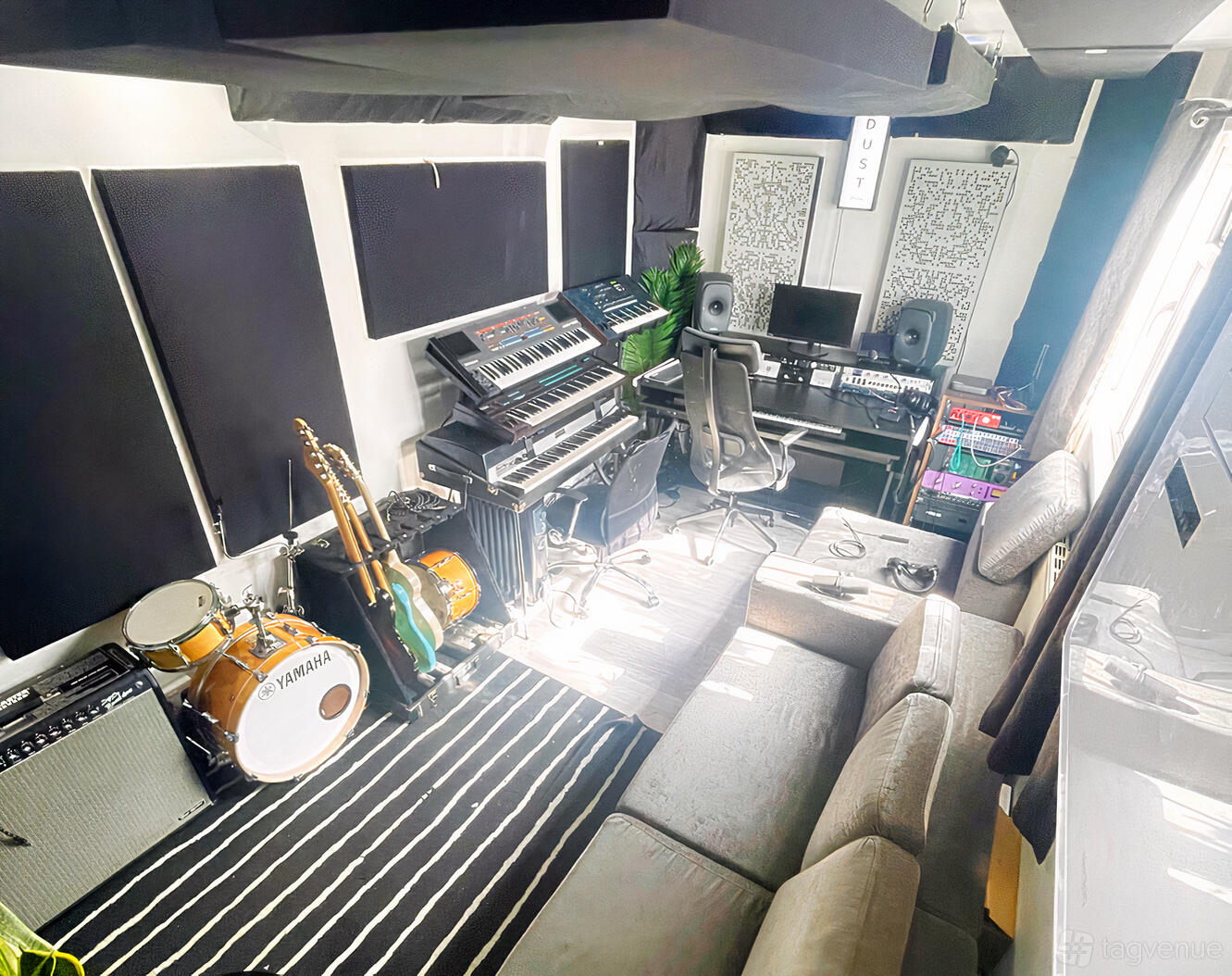 A music studio with soundproofed walls, recording equipment, keyboards, and guitars at The Dust Studios.