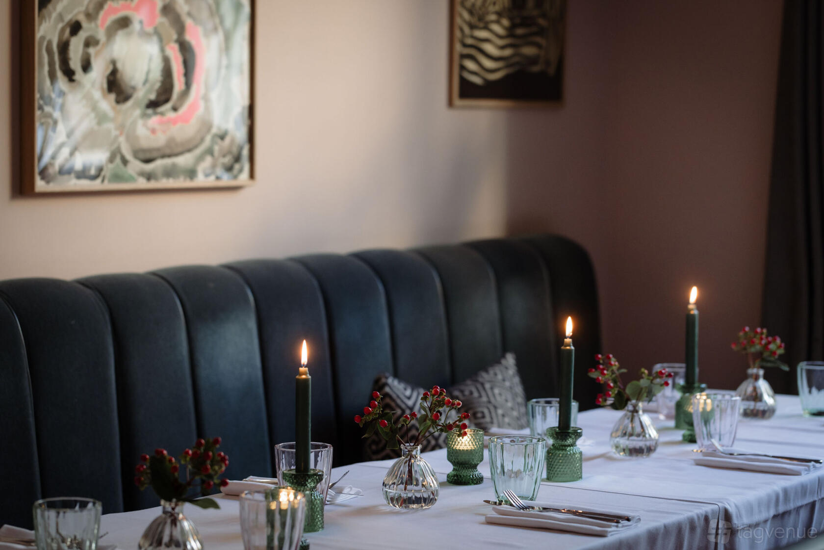 A hotel bar with dark upholstered banquette seating, candlelit tables, and framed art at The Laslett