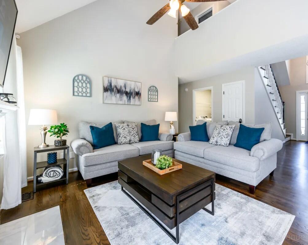 A living room with two gray sofas, blue accent pillows, a wooden coffee table, and decorative wall art at Suite Stays Atlanta - Windfield, Cartersville.