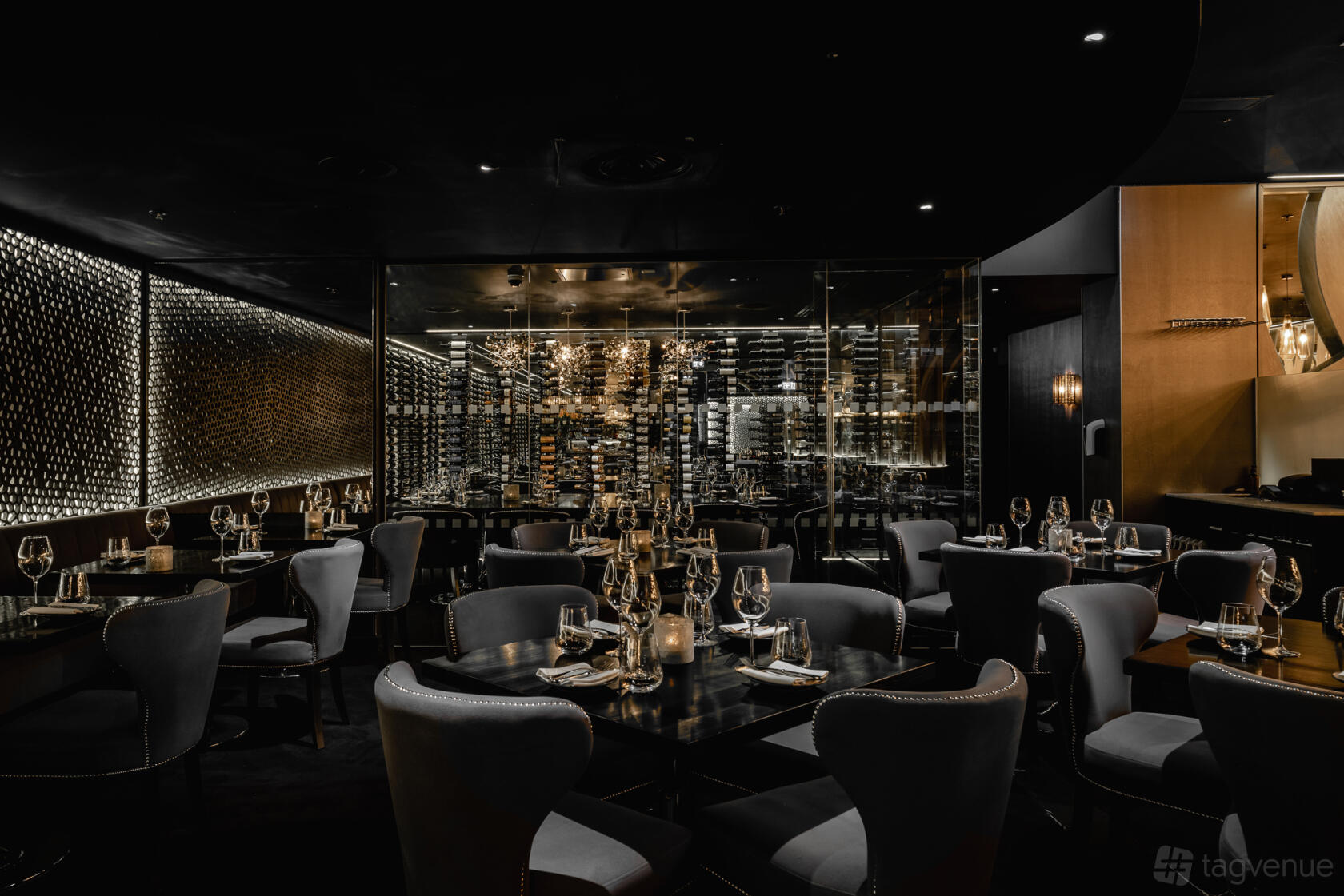 A restaurant with dark elegant decor, candlelit tables, leather chairs, and a feature wine wall at Gaucho Edinburgh.