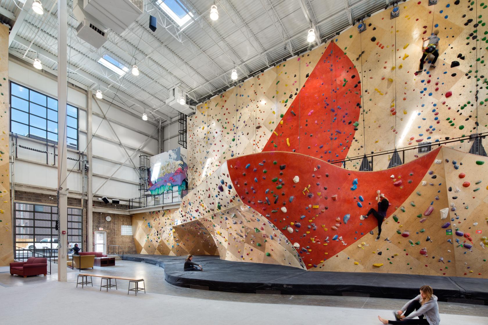 An event space in a sports hall with large climbing walls, bouldering holds, and high ceilings at Brooklyn Boulders West Loop.