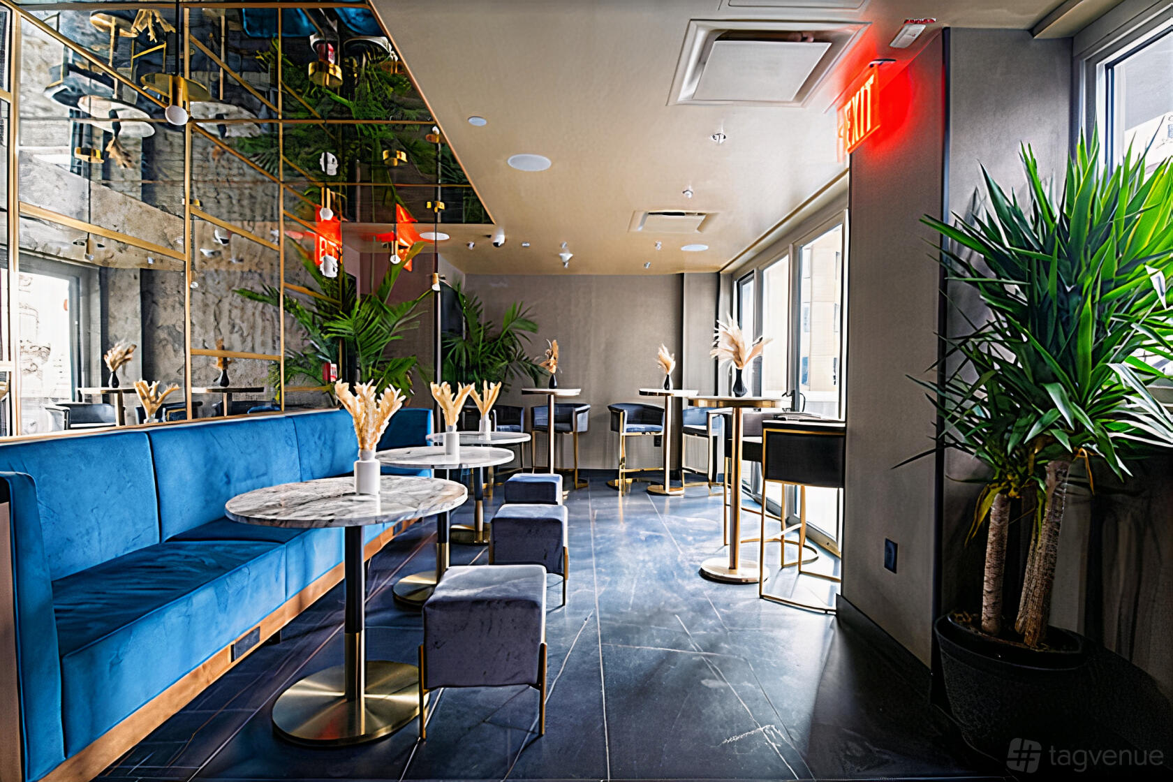 A rooftop bar lounge with blue velvet seating, marble tables, mirrored walls, and potted plants at Highwater Rooftop.