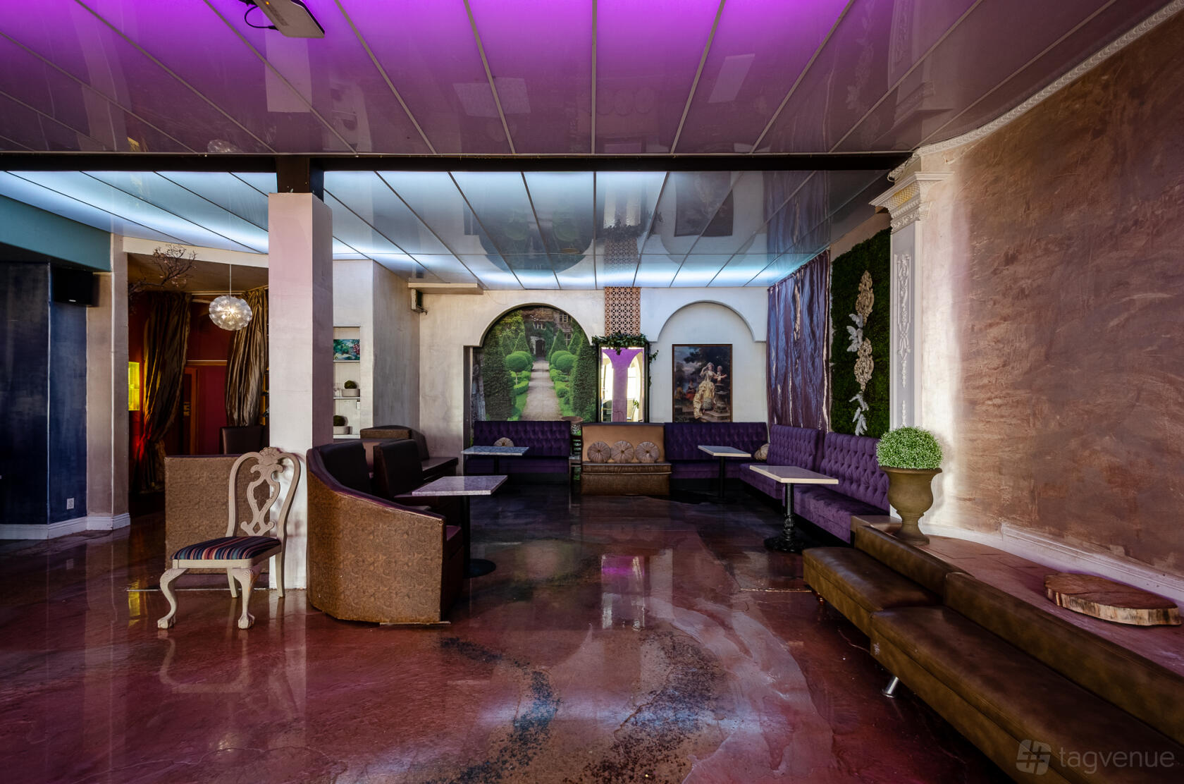 An event space in a restaurant with purple banquette seating, decorative wall murals, and a glossy floor at Madeline Garden.