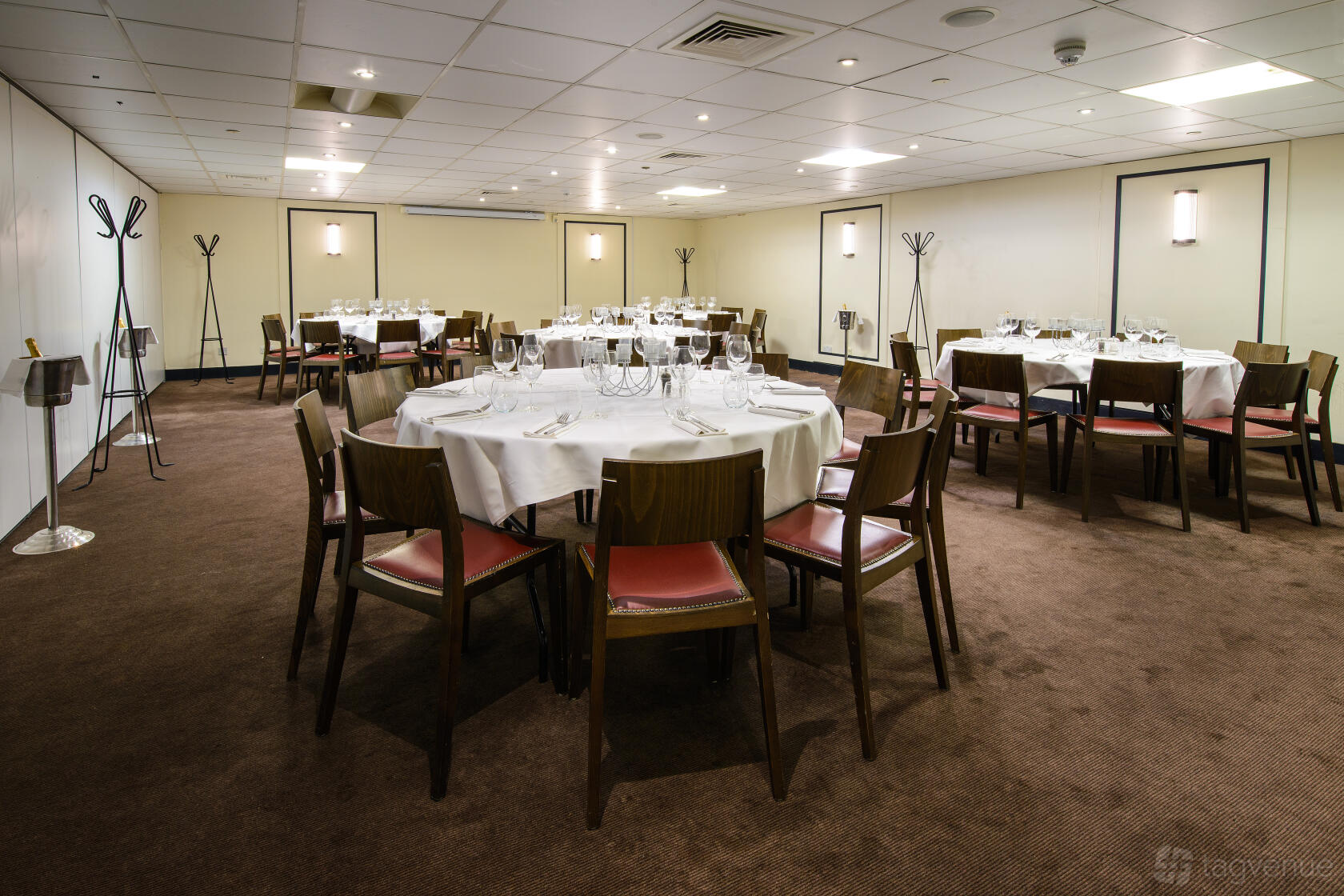 A restaurant with round tables covered in white linens and wooden chairs at Cote Brasserie St. Paul's.
