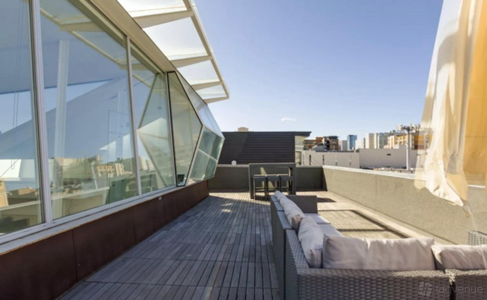 An event space with outdoor wooden decking, modern glass windows, and lounge seating at Alloy Collective.