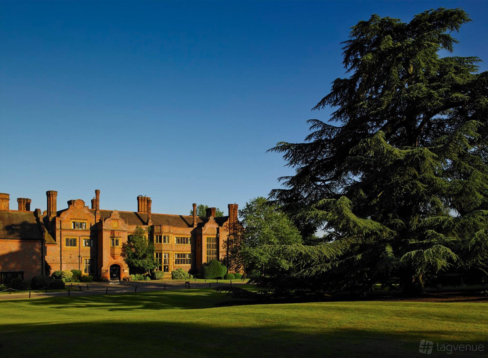 A historic hotel with a red brick facade, large windows, and manicured lawns at Hanbury Manor Marriott Hotel & Country Club.
