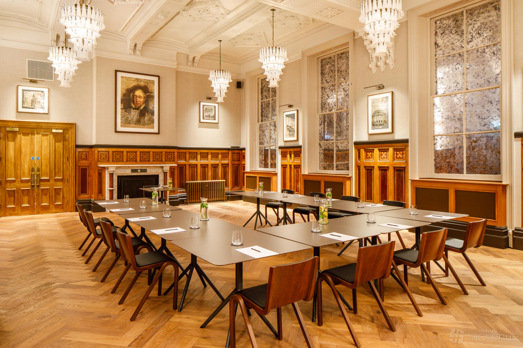 A function room with high ceilings, chandeliers, parquet flooring, and U-shaped tables at Municipal Hotel Liverpool - MGallery.