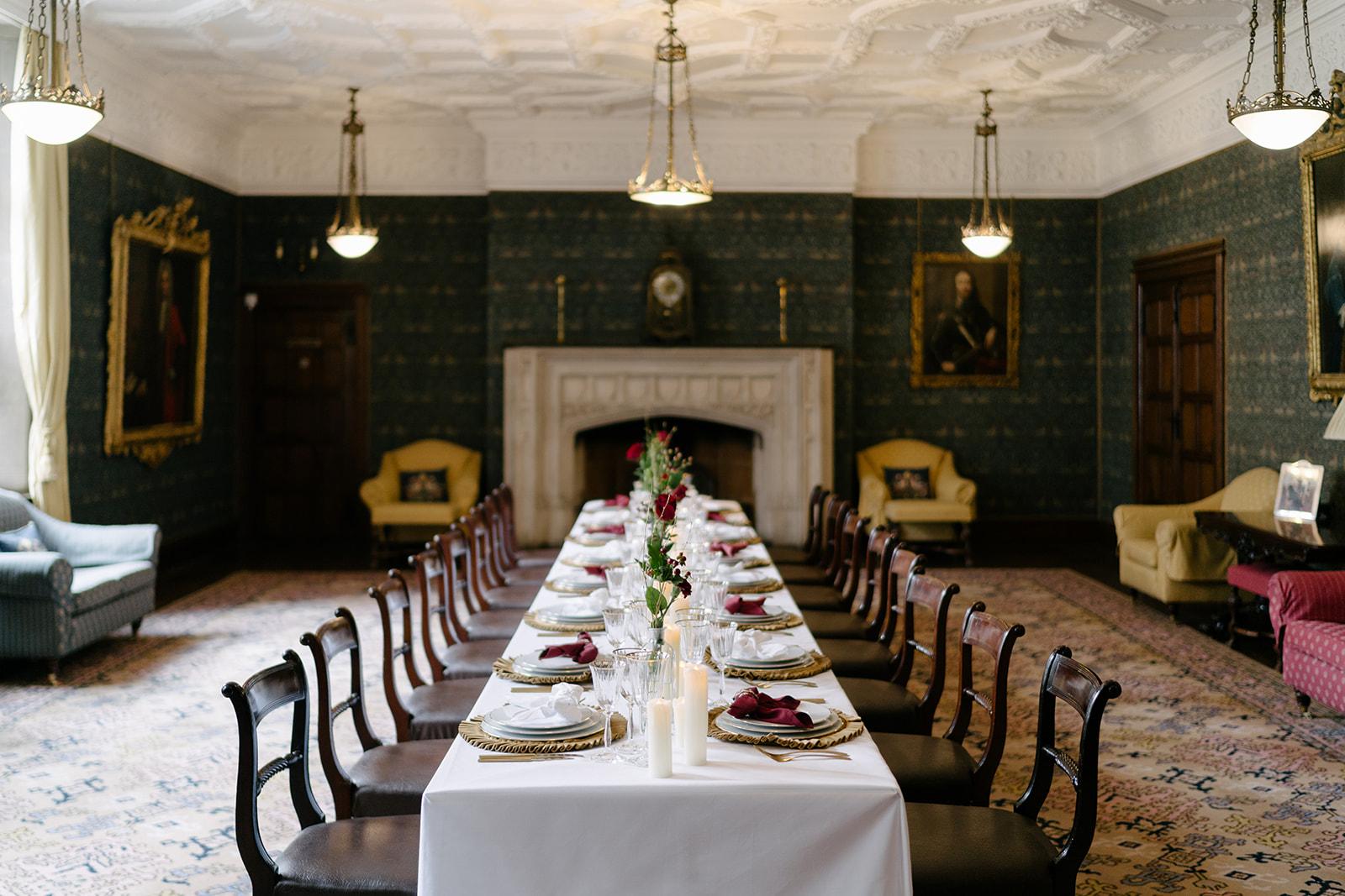An event hall with ornate ceiling, fireplace, chandeliers, and long banquet table set in the Drawing Room at Ironmongers' Hall.