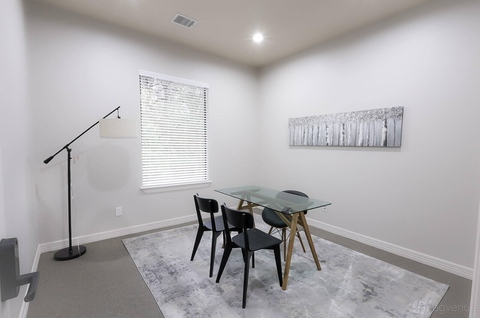 An office space with a glass table, four black chairs, an area rug, and a floor lamp at Magnolia Woods Office Suites- Montgomery.
